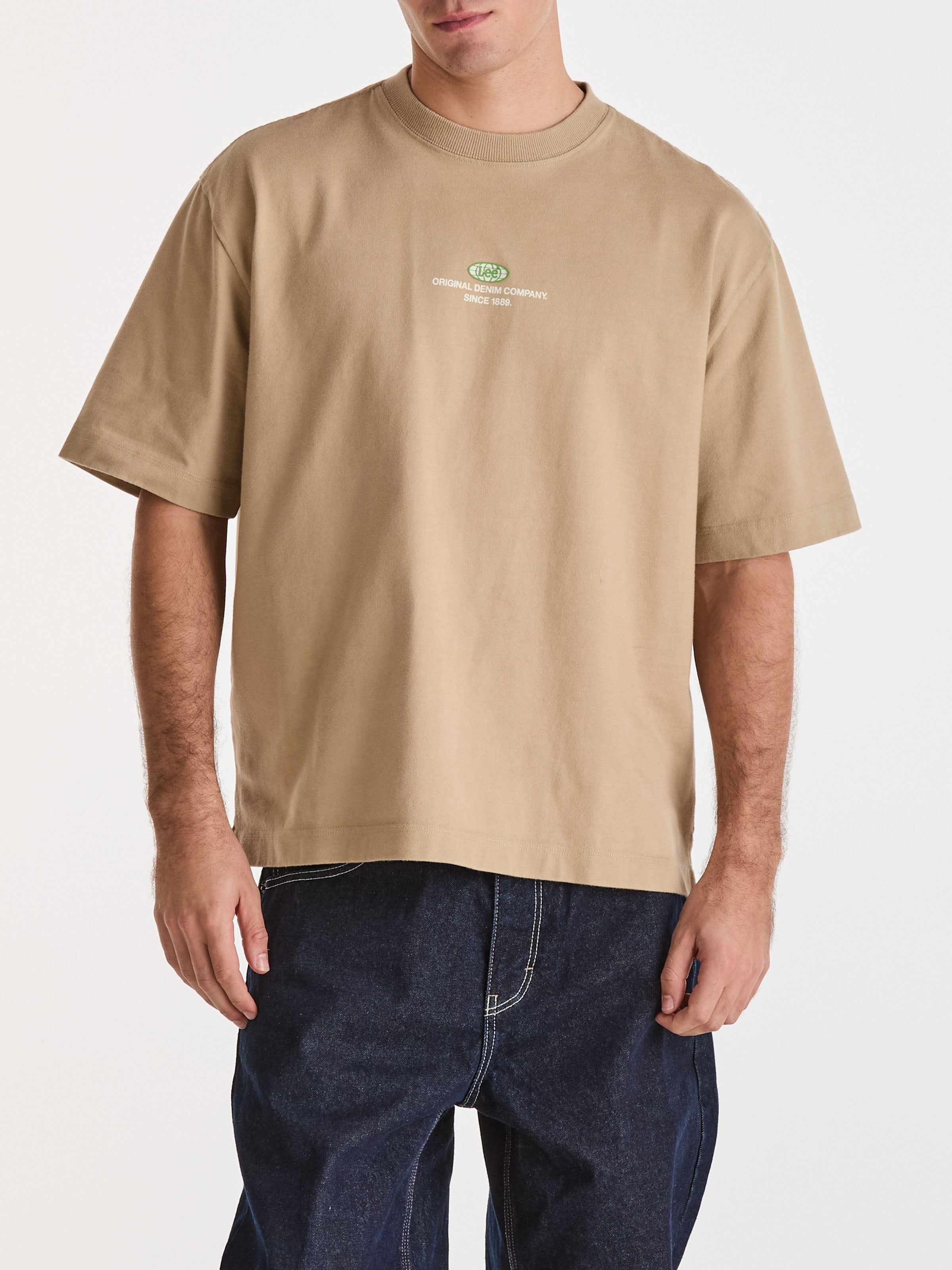 Person wearing a beige t-shirt with a logo on a white background