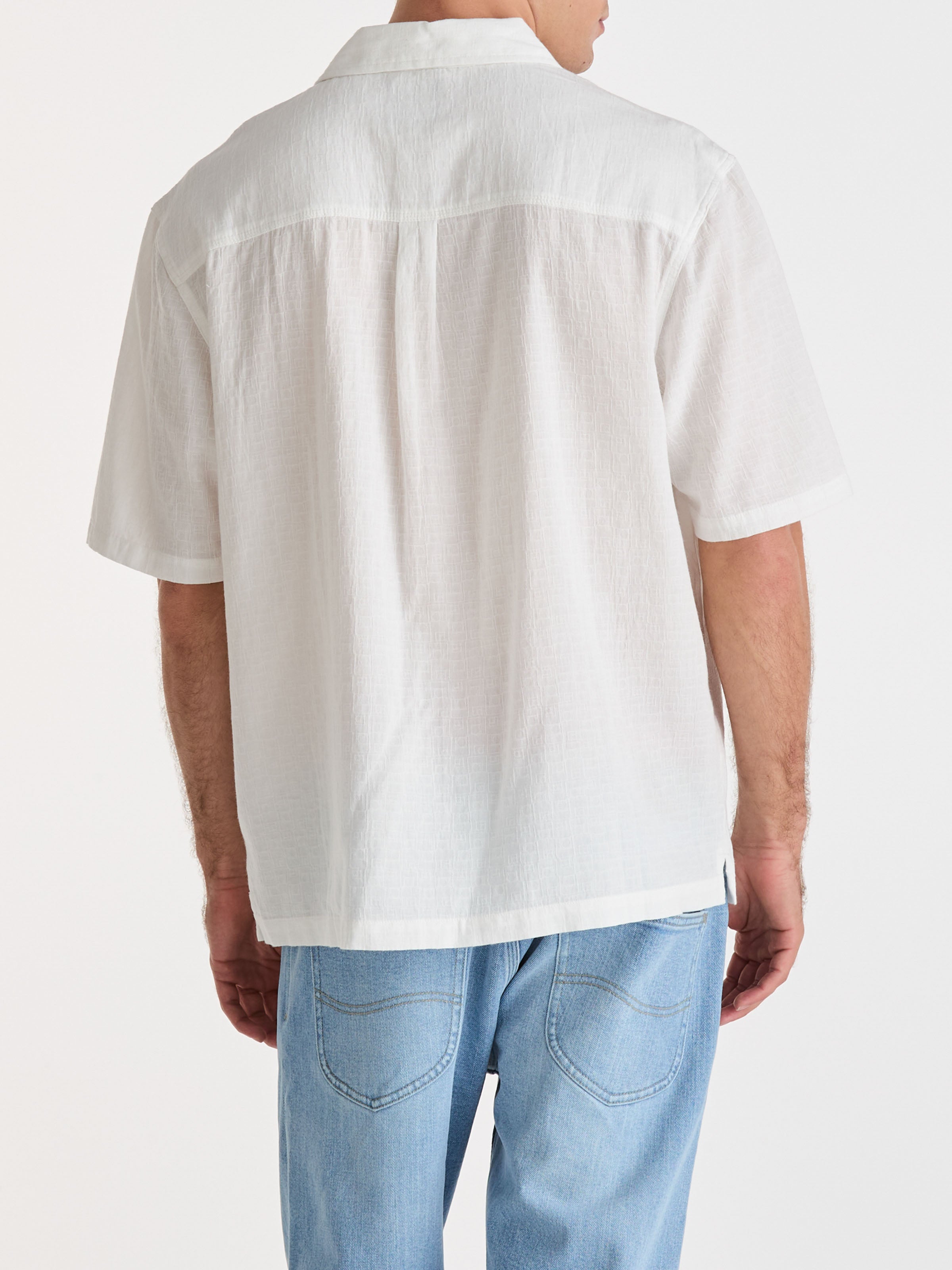 Person wearing a white short-sleeve shirt and light blue jeans on a white background