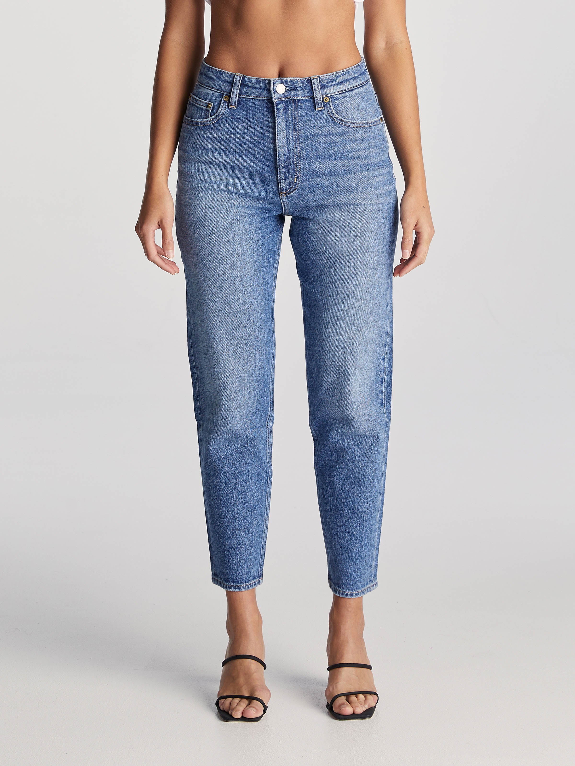 Denim jeans sit high on the waist, with a slim leg that tapers to the hem, finishing at a slightly cropped, ankle skimming length