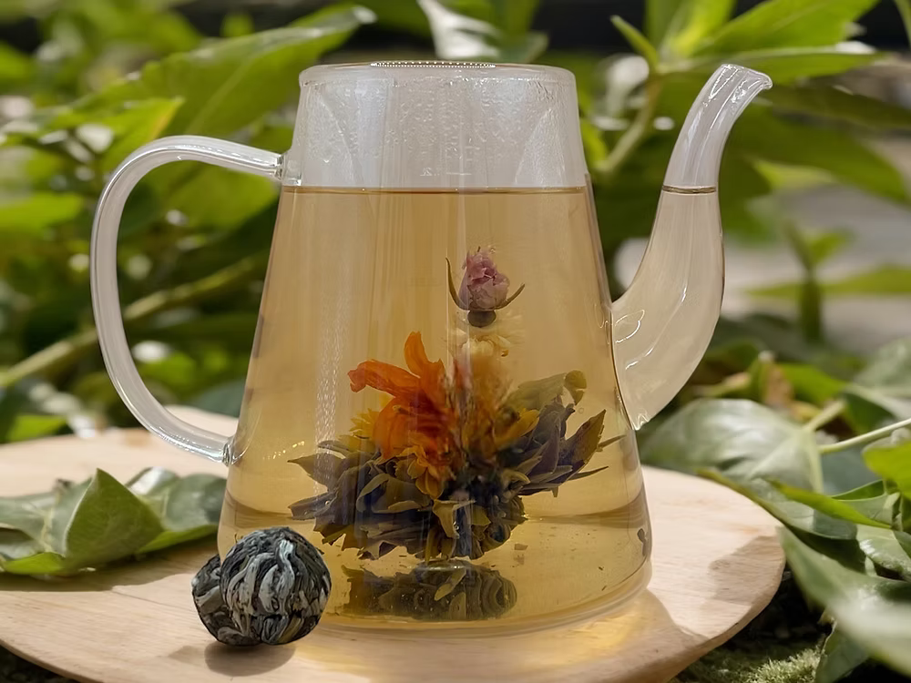 Clear teapot with floral tea  green leaves 