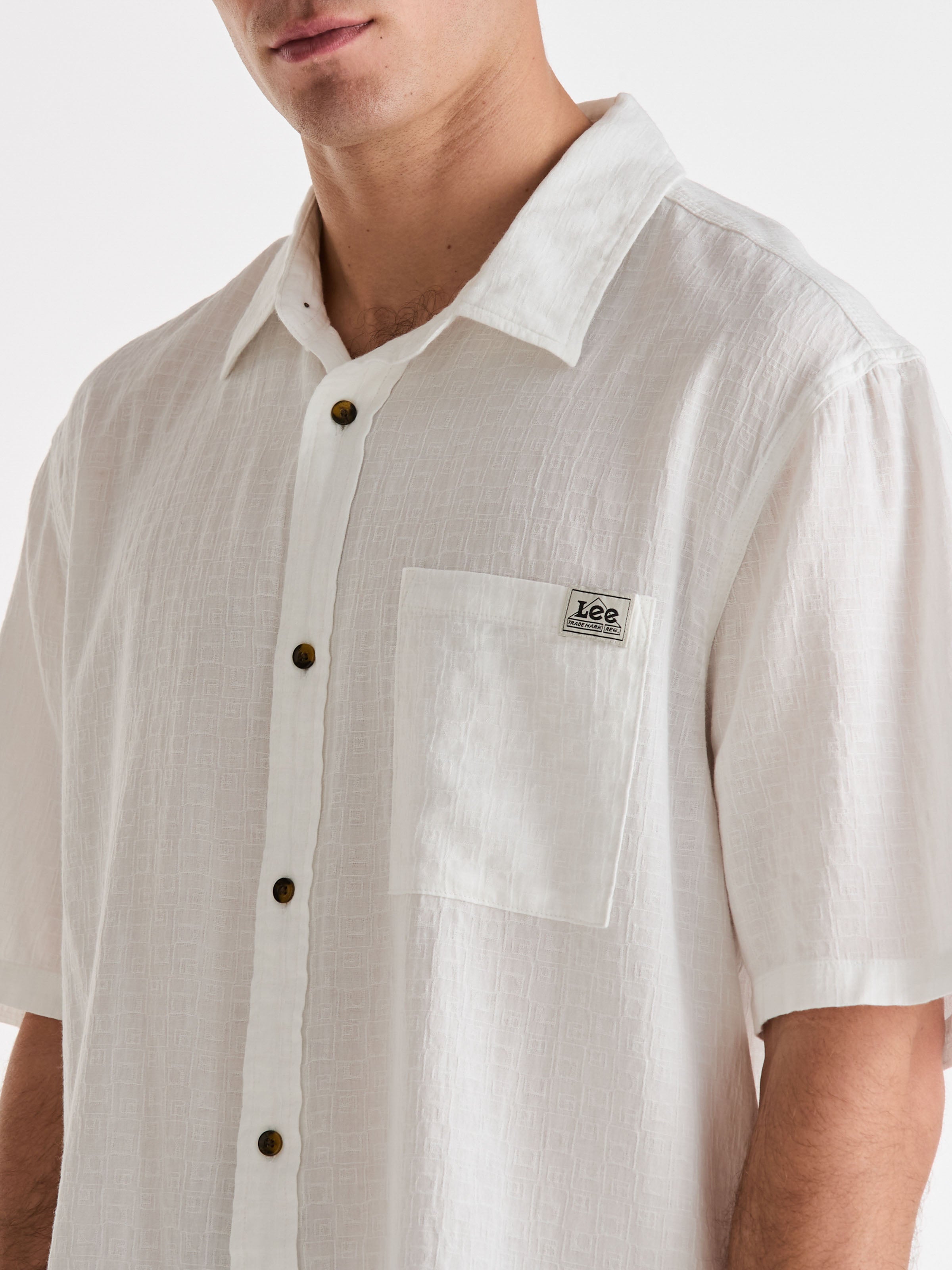 White button-up shirt with a visible brand logo on a plain background